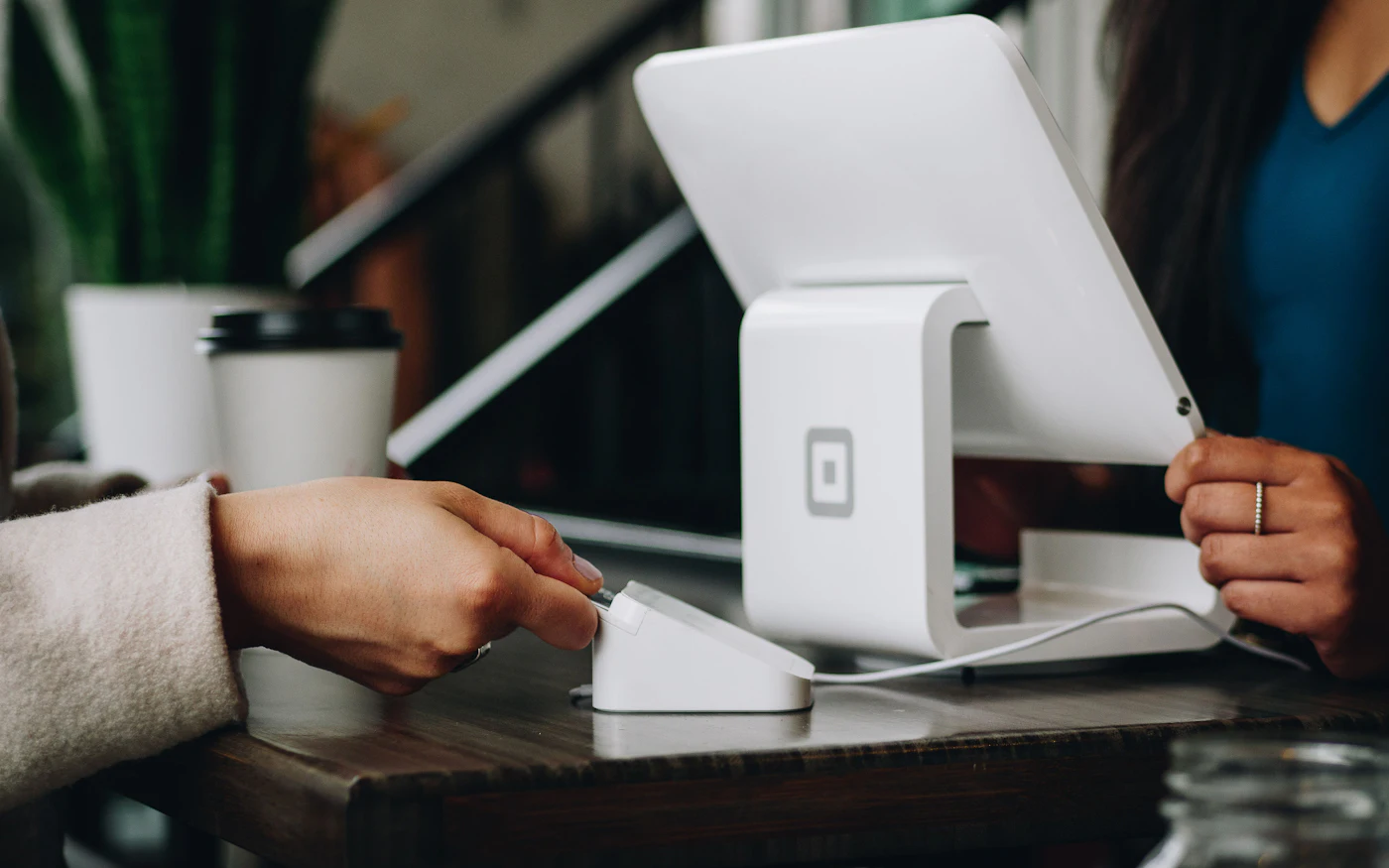 Customer tapping a card on a payment terminal at a counter