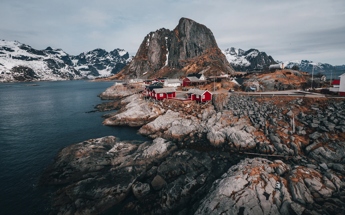 Small fishing village on a rocky coast below snowy mountains