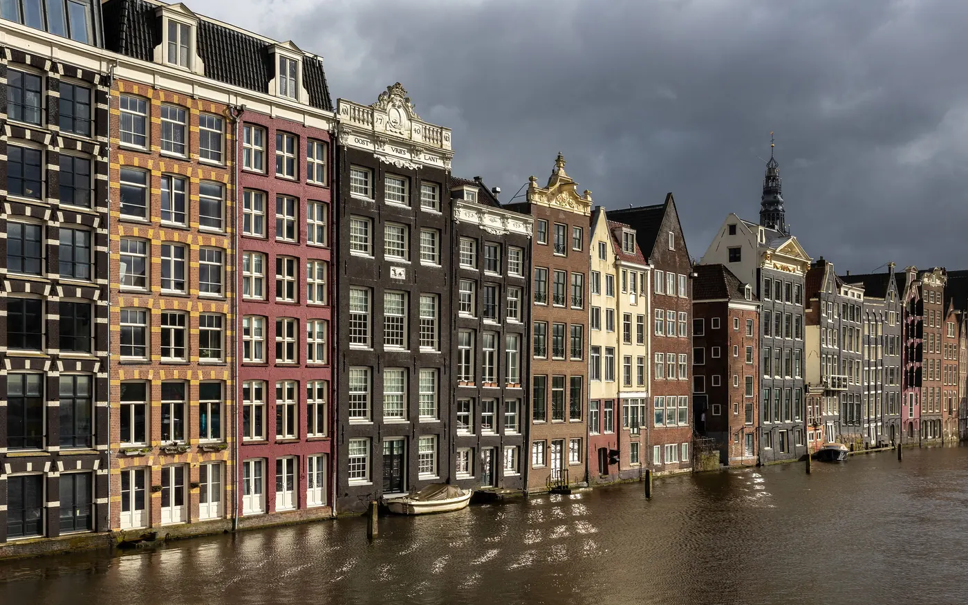 Colorful canal houses along the Damrak in Amsterdam at golden hour