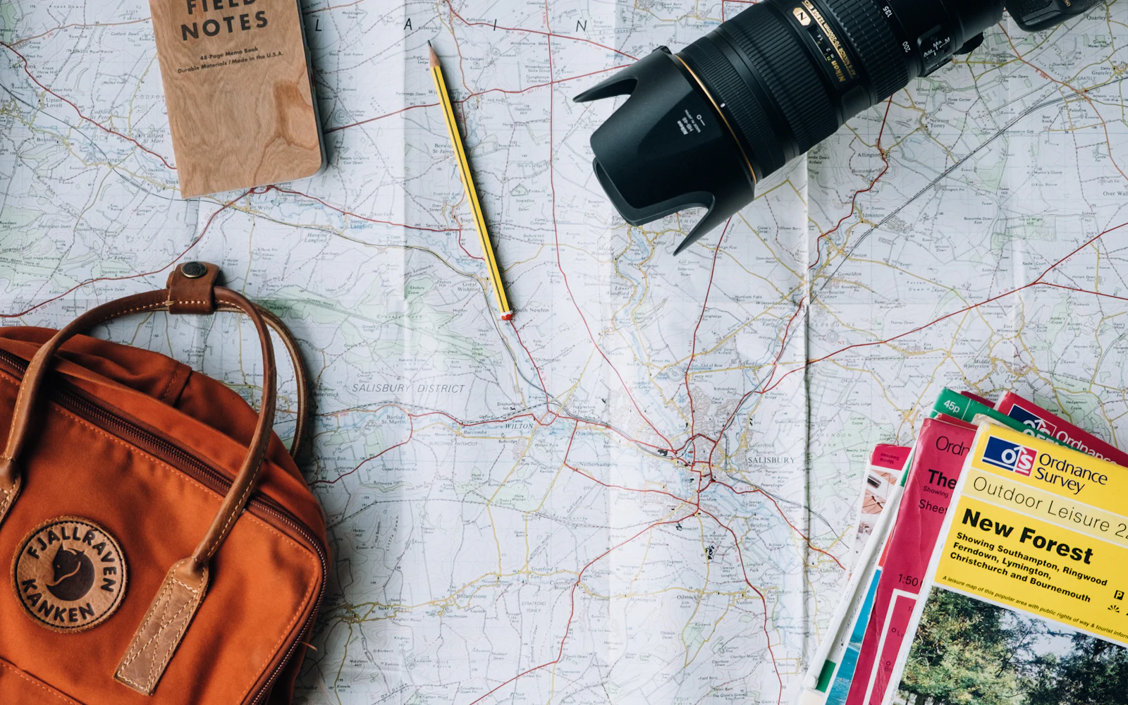 Paper map spread out with a travel bag, notebook, camera lens and guidebooks