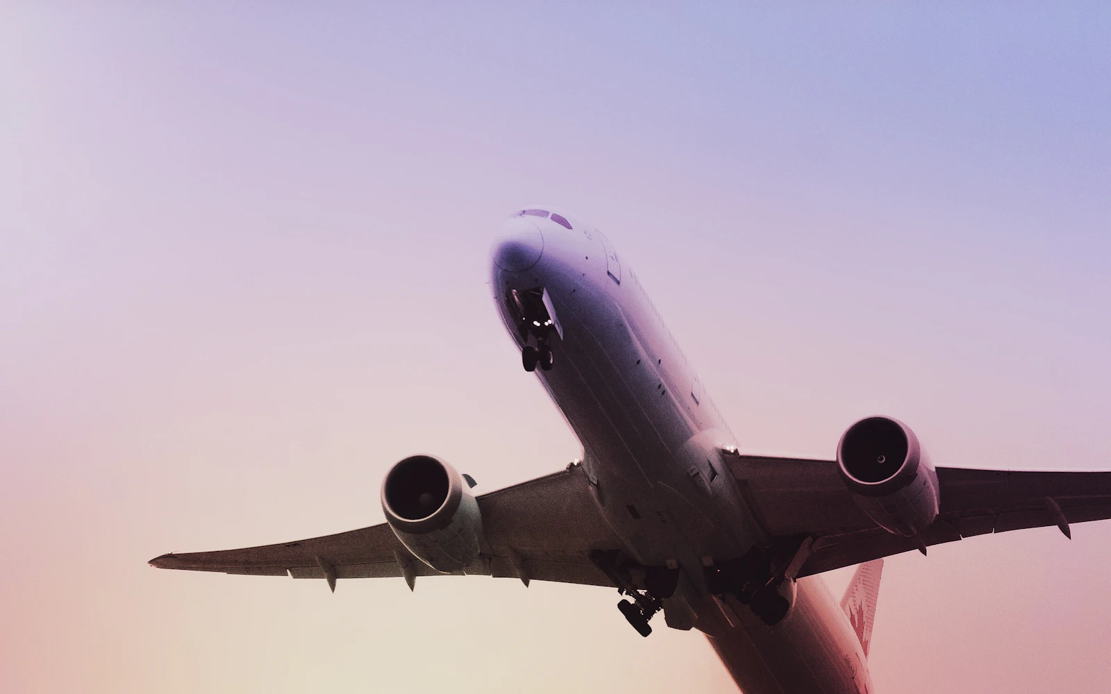 Passenger plane flying overhead against a pink evening sky