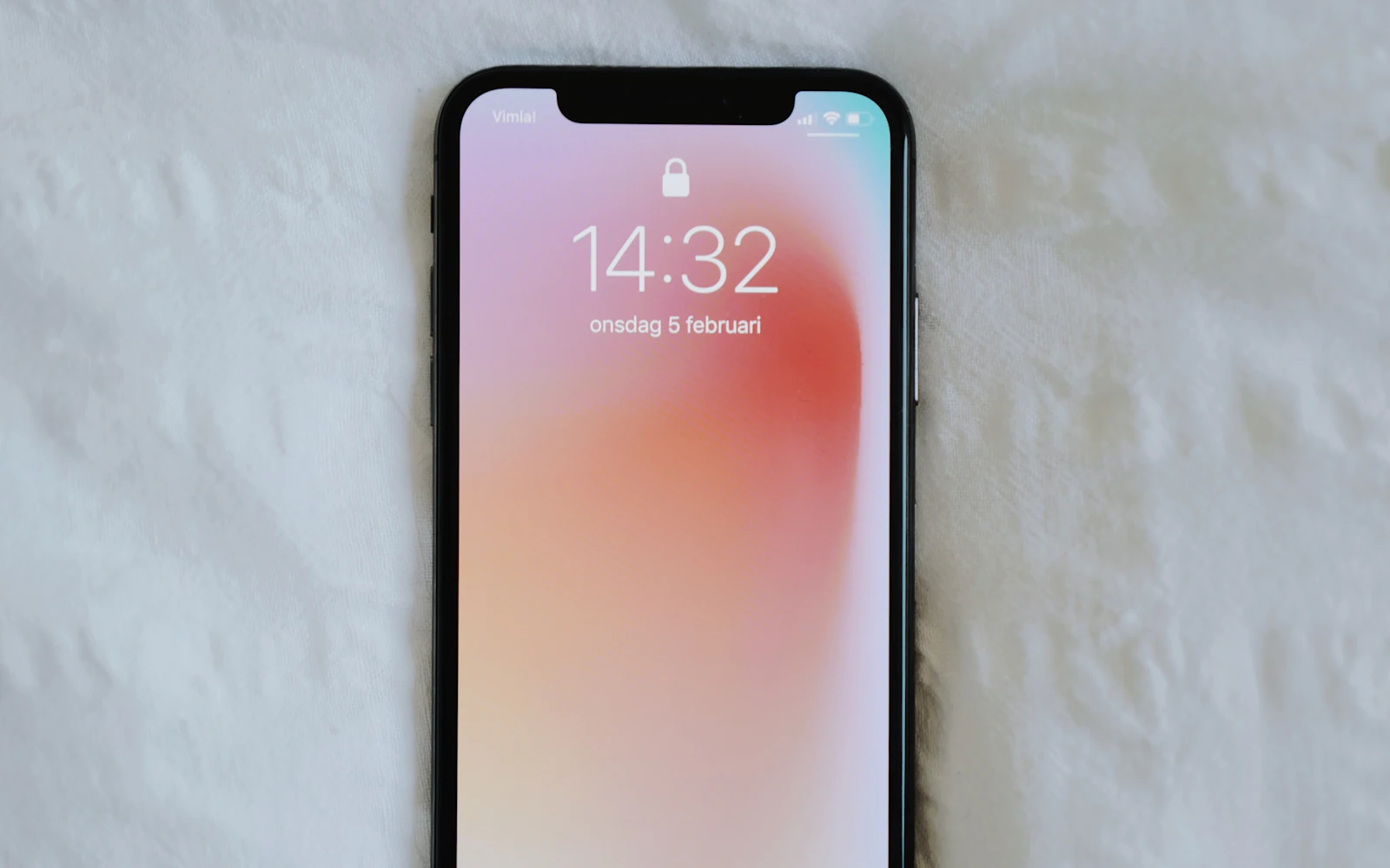 Smartphone lying face up on white bed sheets