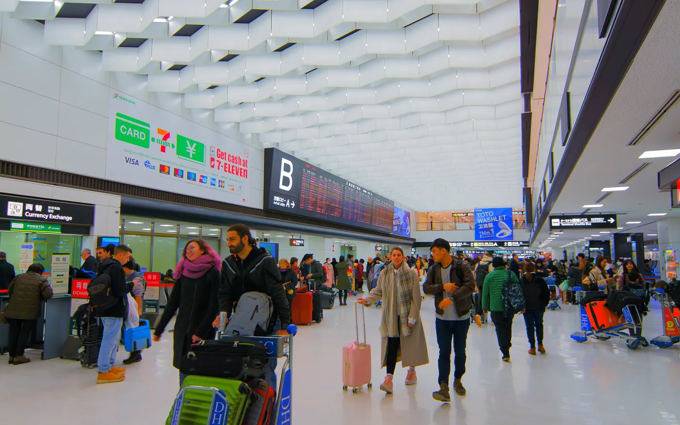 Travelers with luggage in the arrivals lobby of Narita Airport Terminal 2