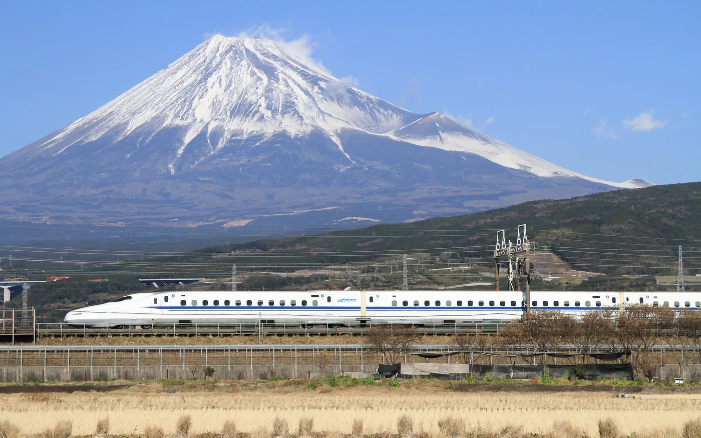 A Shinkansen bullet train passing in front of snow-capped Mount Fuji