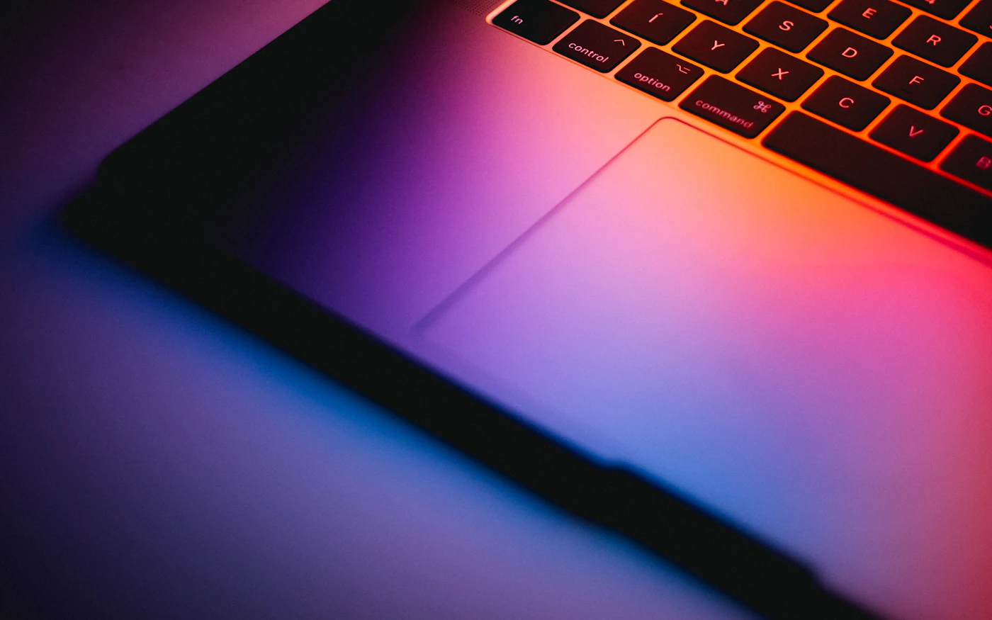 Laptop keyboard lit by a colourful screen glow