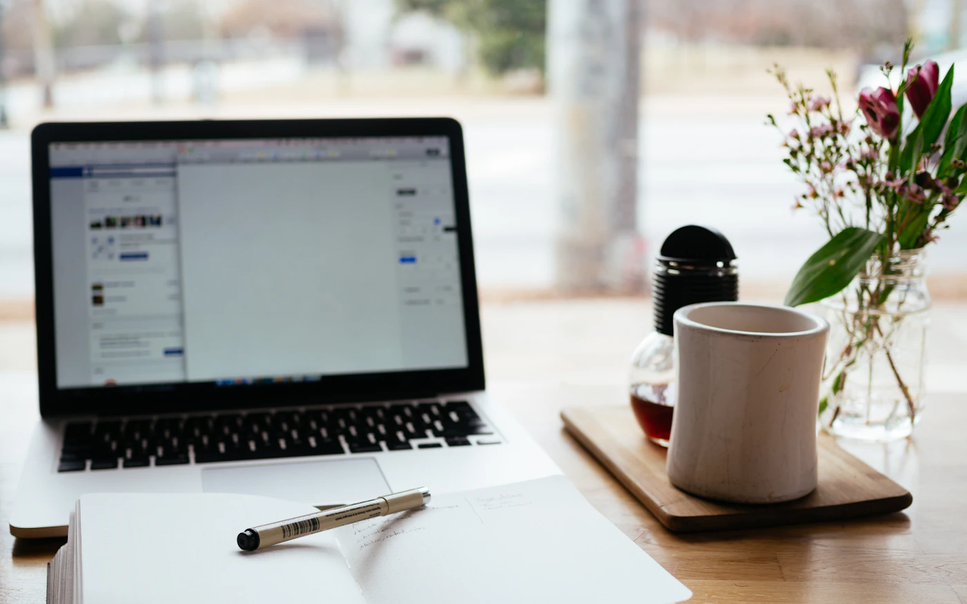 Laptop, notebook and coffee mug on a desk at home