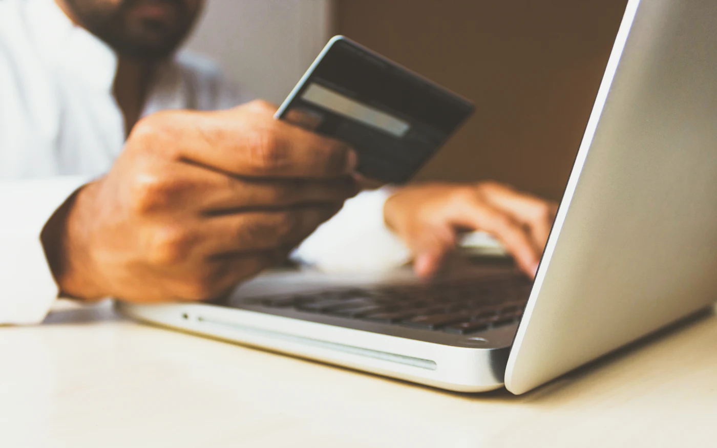 Person holding a payment card while using a laptop
