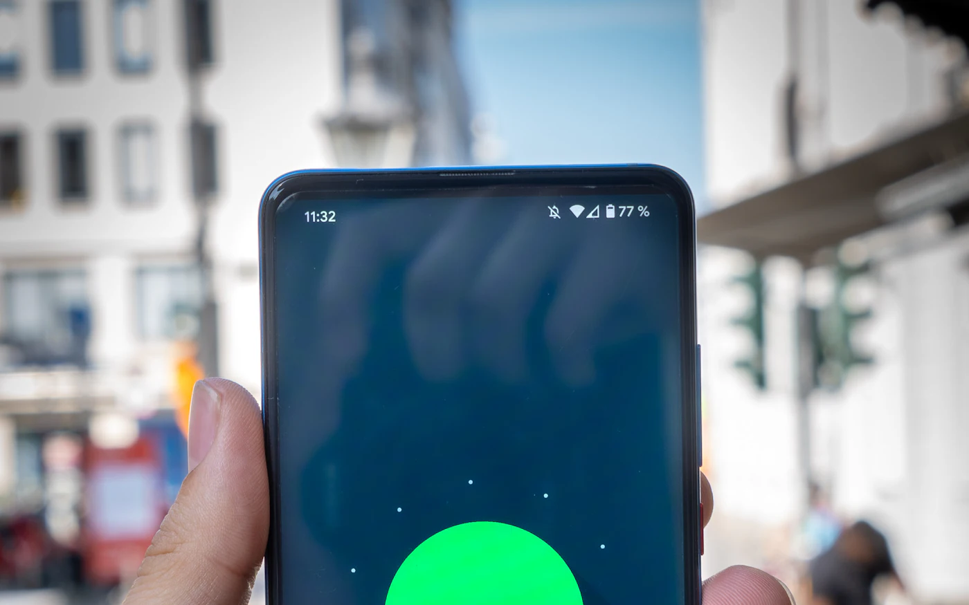 Hand holding a phone on a busy city street