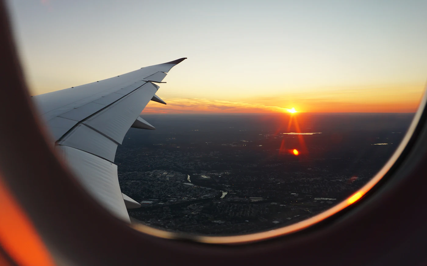 View of a sunset over the clouds through an airplane window