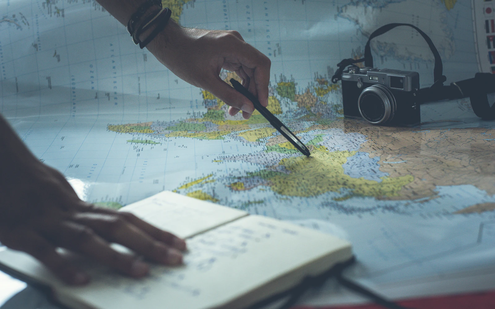 Traveler planning a route on a paper map with a camera and notebook nearby