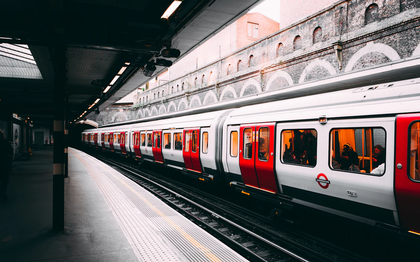 Passengers on a train station platform beside a red and white train