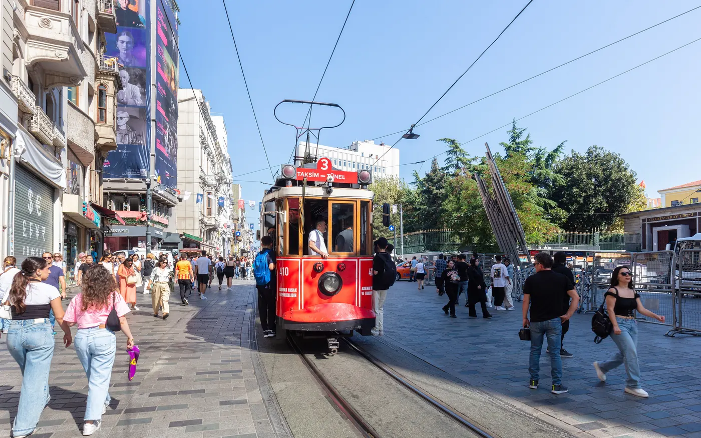 A red nostalgic tram on Istiklal Avenue in Istanbul, surrounded by pedestrians