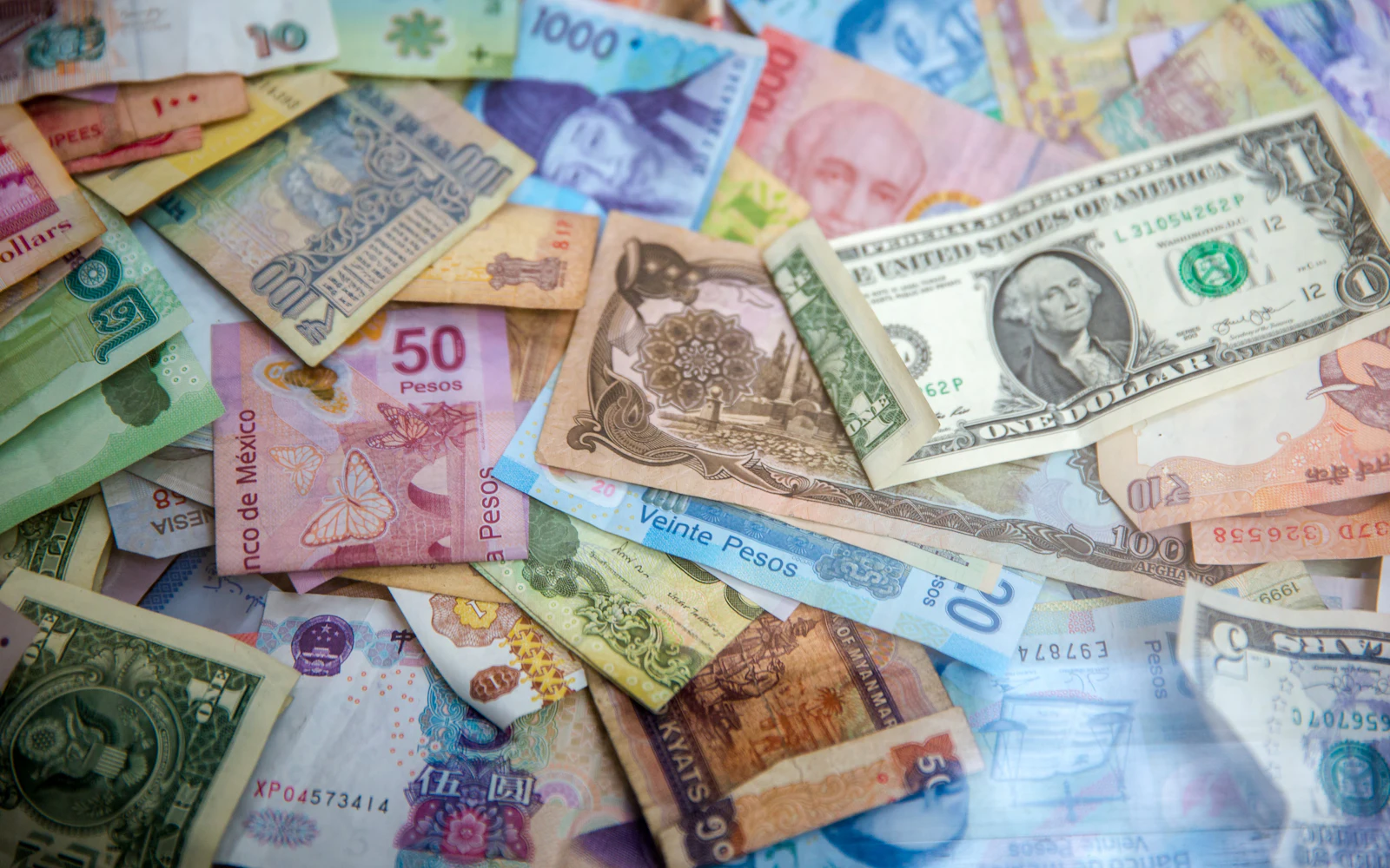Banknotes in many different currencies spread across a table