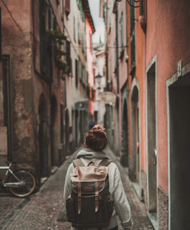 Traveler with a backpack walking through a narrow old town street