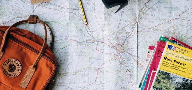 Travel planning flat lay with a map, camera and backpack