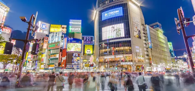 Crowds crossing Shibuya Crossing in Tokyo at dusk