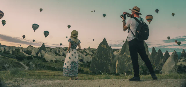 Travelers watching hot air balloons over a valley